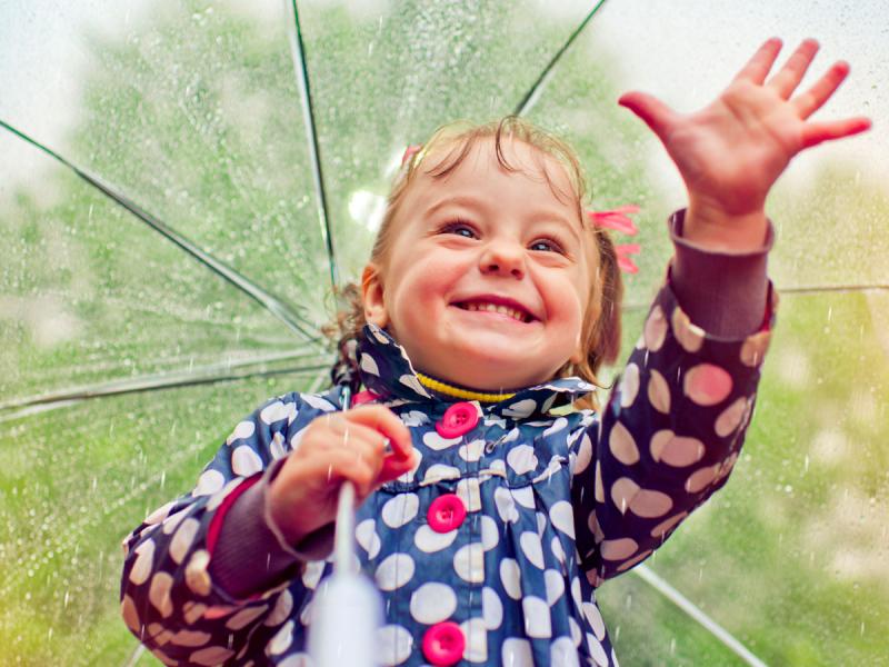 Girl with umbrella smiles and reaches out