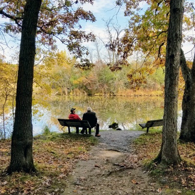 Friends relax on bench at river's edge