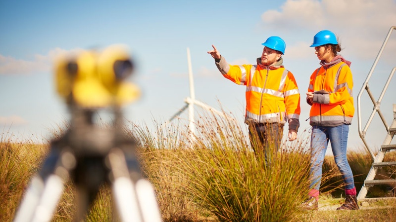Two workers walk near wind turbine