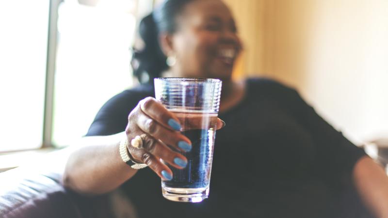 smiling woman holds glass of water