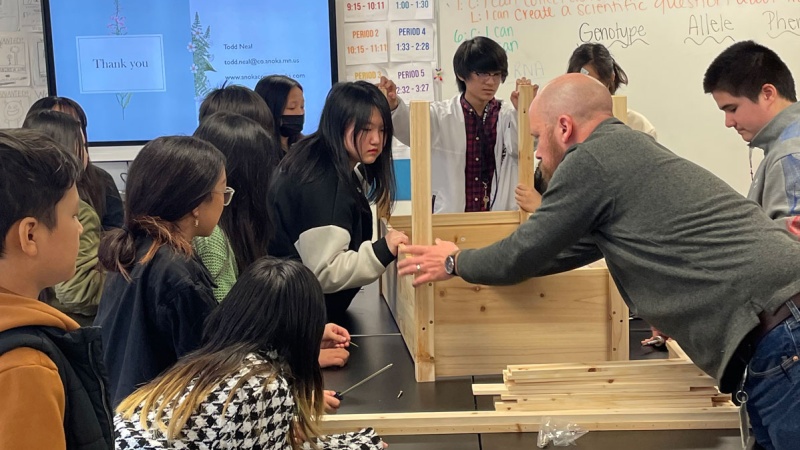 Teacher works with students on carpentry project