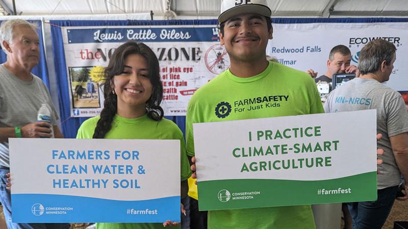two people hold signs supporting climate-smart agriculture