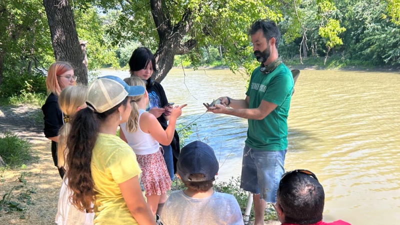 Adult teaches group of kids how to fish