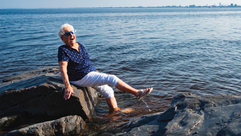 Joyful senior dipping feet in Lake Superior in Duluth