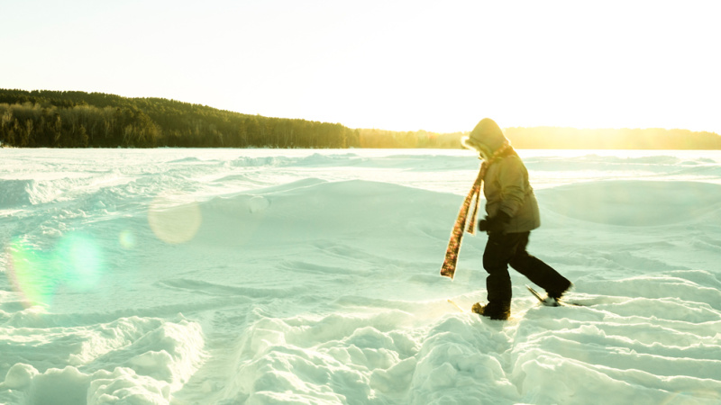 Person snowshoeing on a snowy lake in winter.
