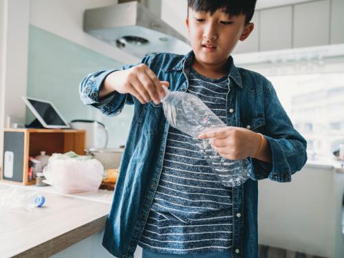 Boy with plastic bottle in kitchen