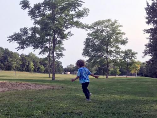 Child runs in park field
