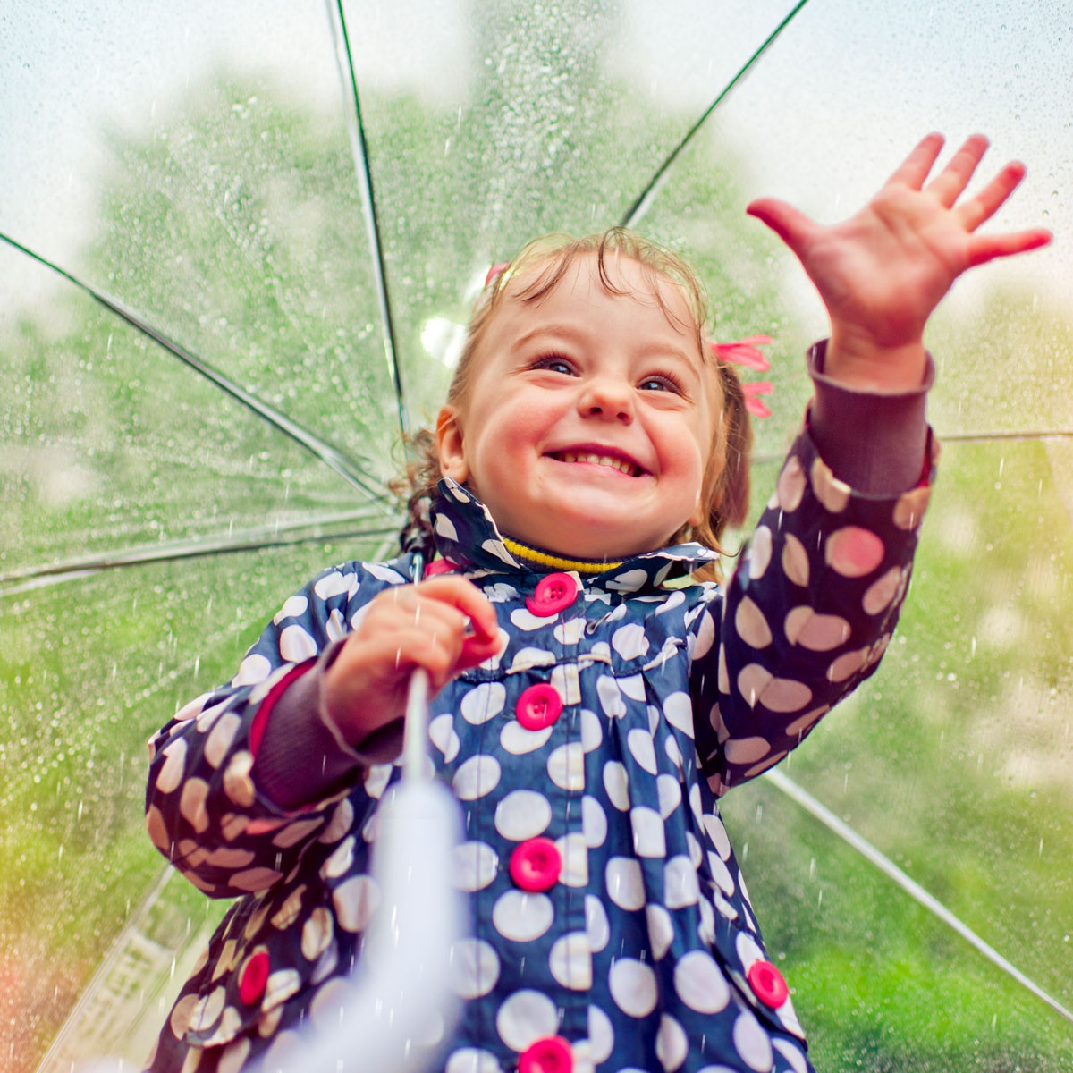 Girl with umbrella smiles and reaches out