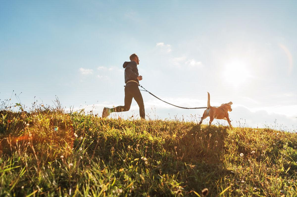 man runs with dog in sunshine