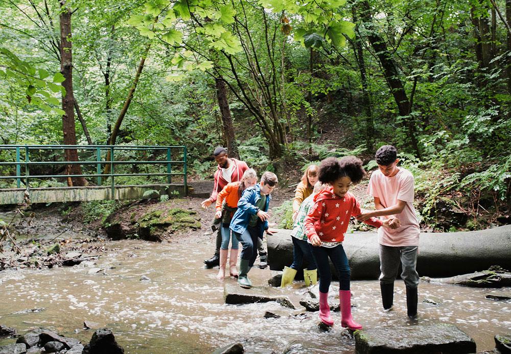 Kids and adults cross a stream