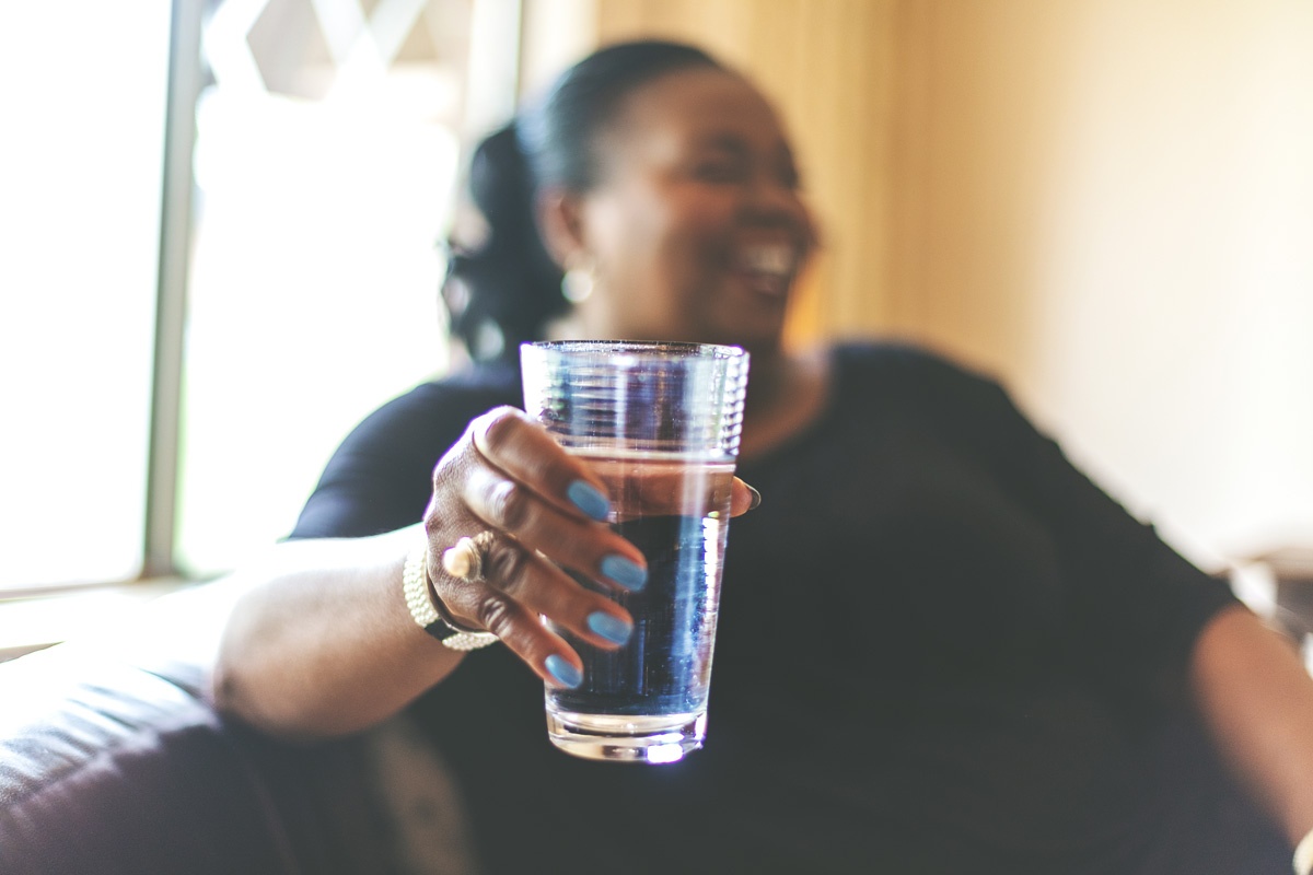 smiling woman holds glass of water