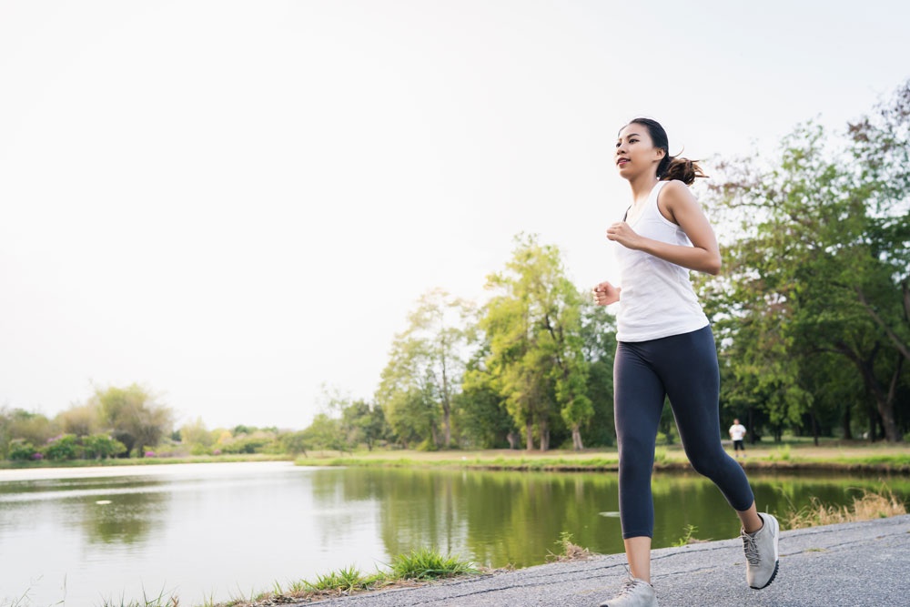 woman runs on path near lake in springtime