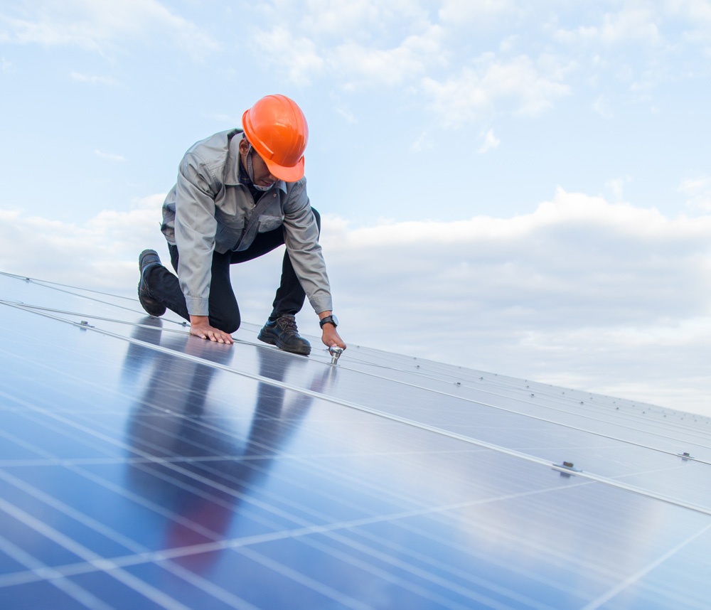 Worker in hard hat works on solar panel