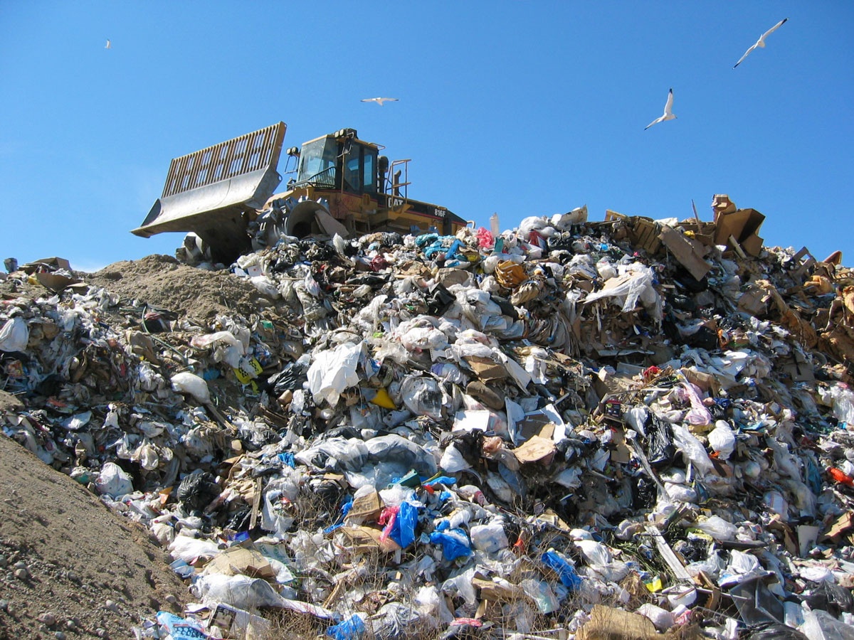 bulldozer on top of pile of garbage in landfill