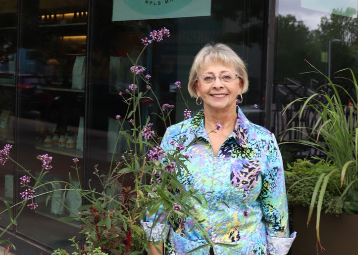 Linda Larson stands among flowering plants