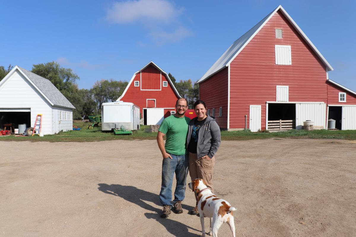 Farmer couple with their dog on by their barn