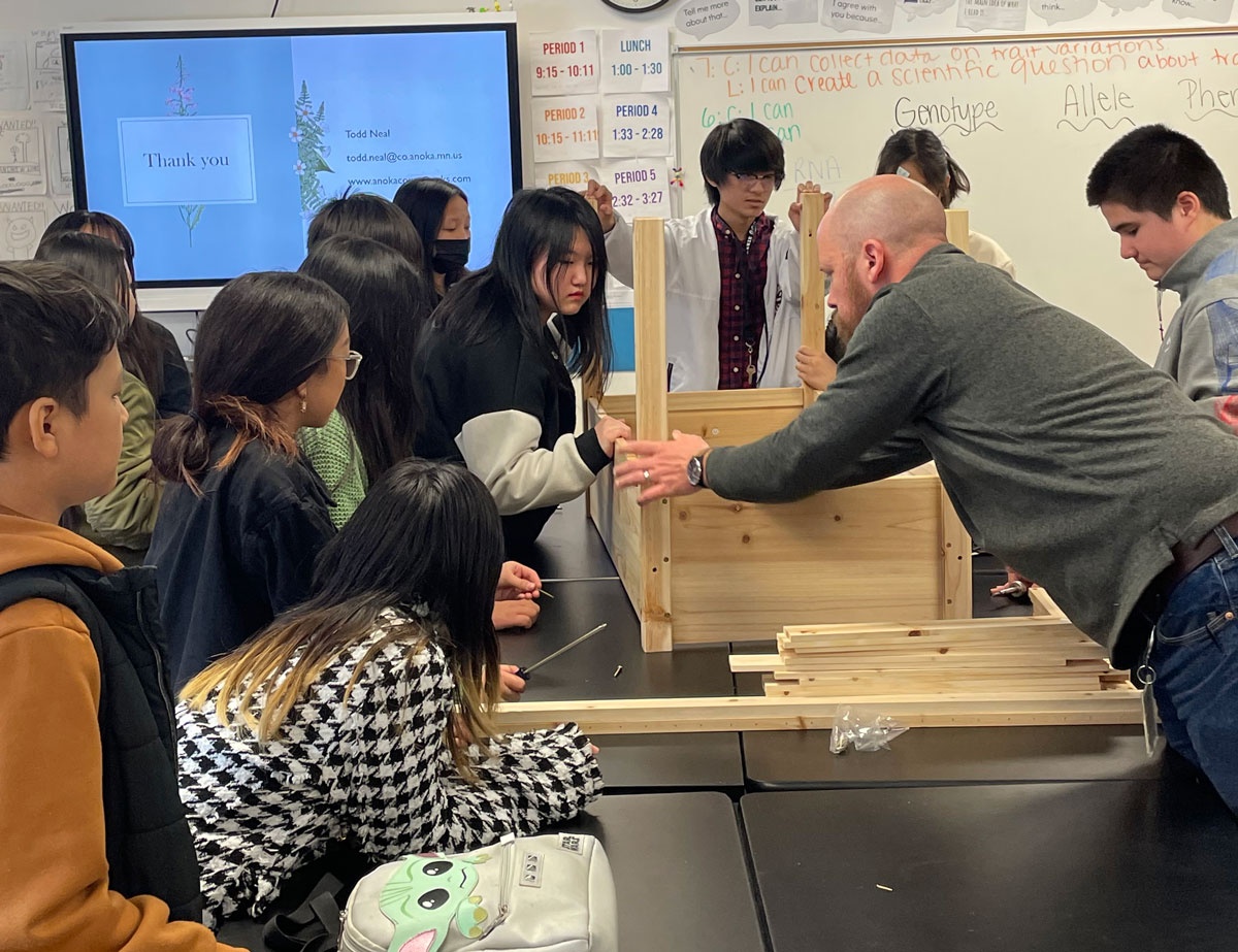 Teacher works with students on carpentry project