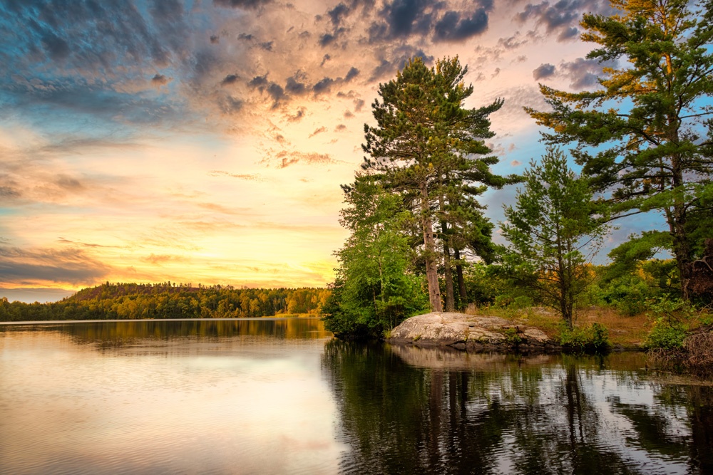 sunrise over lake shore with evergreens