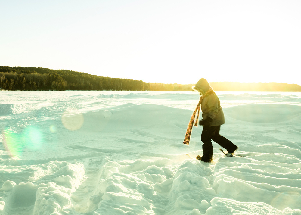 Person snowshoeing on a snowy lake in winter.