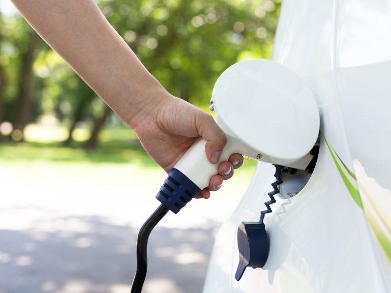 Close up of hand charging electric vehicle