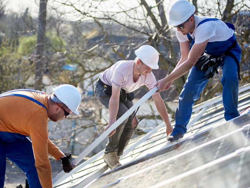 Three men installing solar panels