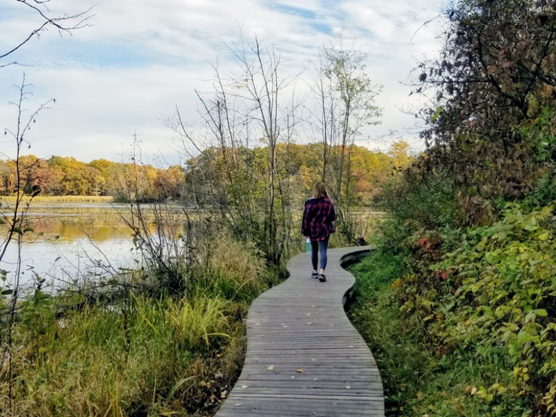 woman walks along boardwalk next to lake