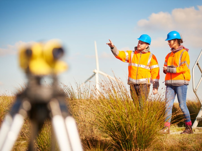 Two workers walk near wind turbine