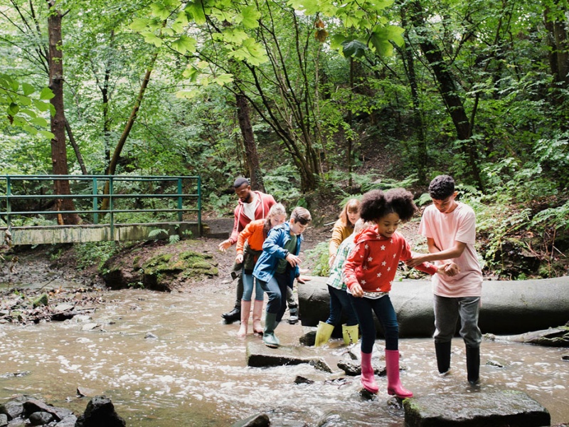 Kids and adults cross a stream