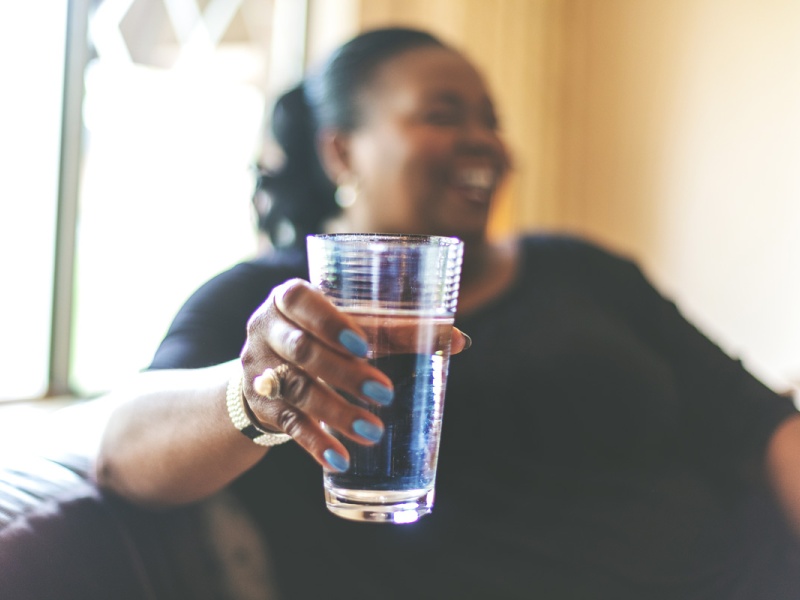 smiling woman holds glass of water