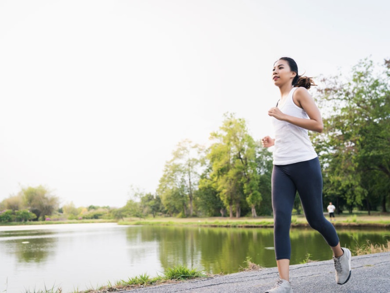 woman runs on path near lake in springtime