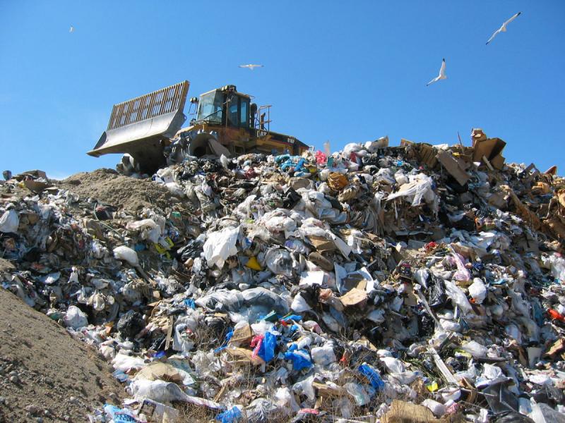 bulldozer on top of pile of garbage in landfill