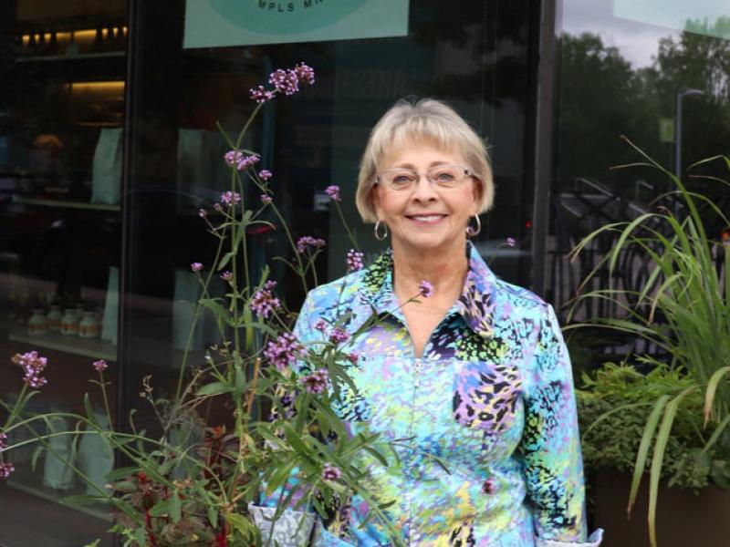 Linda Larson stands among flowering plants
