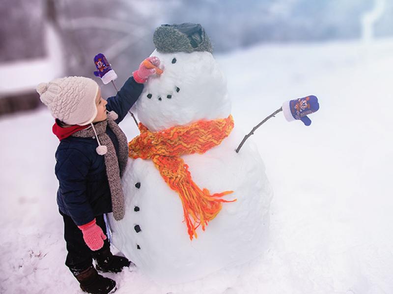 Kid places carrot nose on snowman