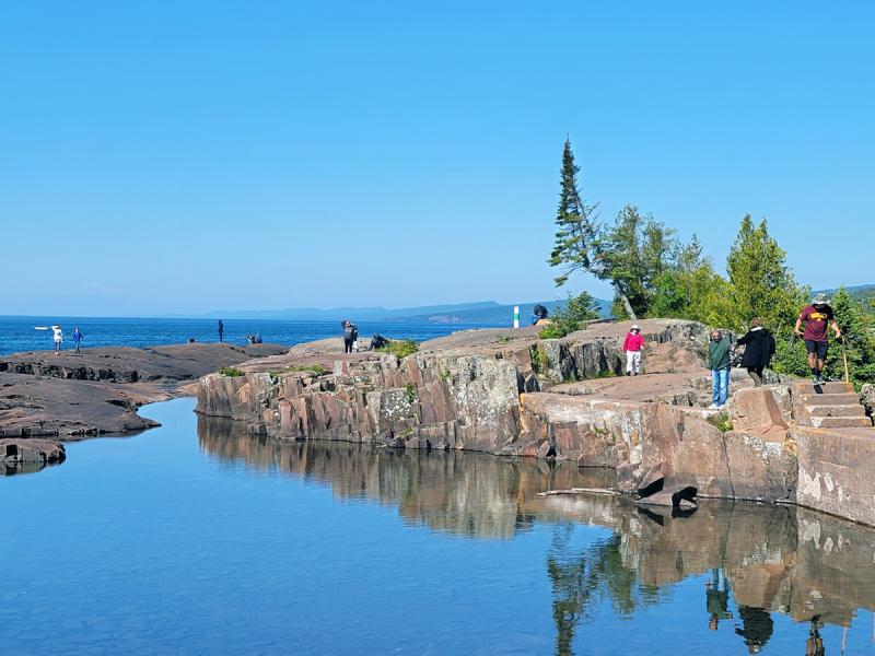 Visitors walk along the edge of Lake Superior