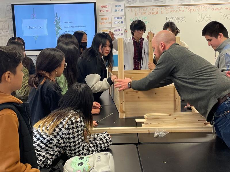 Teacher works with students on carpentry project