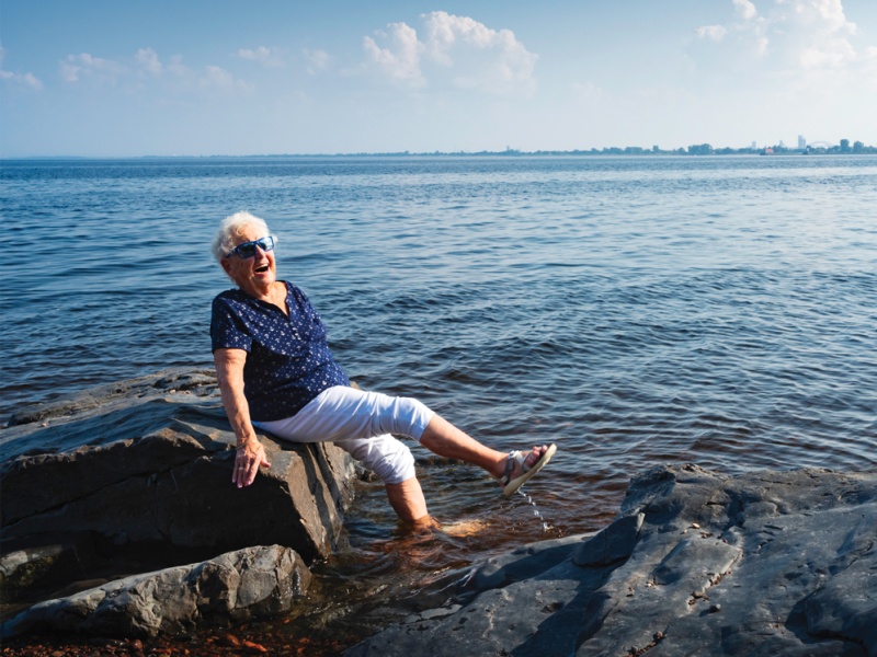 Joyful senior dipping feet in Lake Superior in Duluth