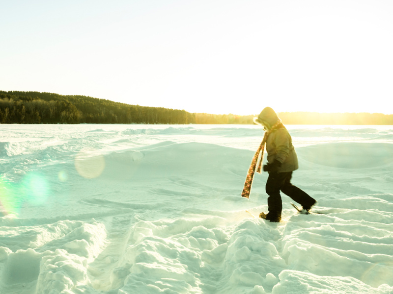Person snowshoeing on a snowy lake in winter.