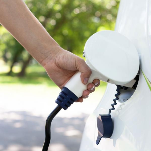 Close up of hand charging electric vehicle