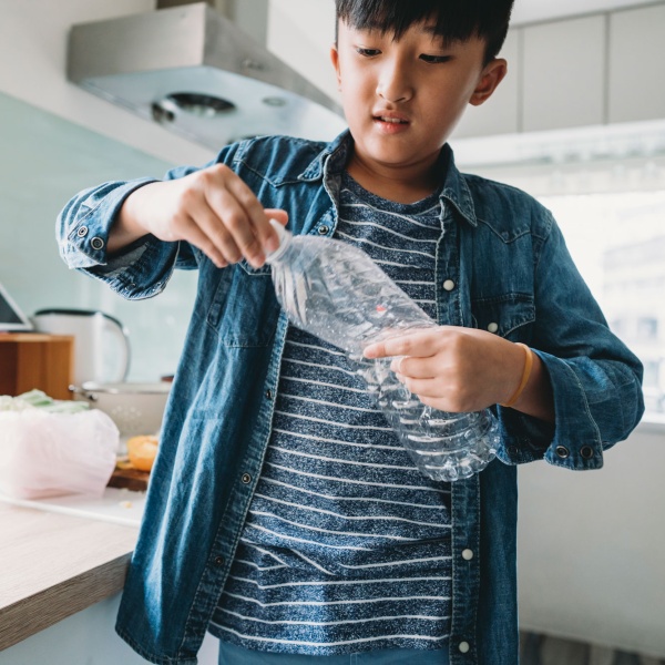 Boy with plastic bottle in kitchen