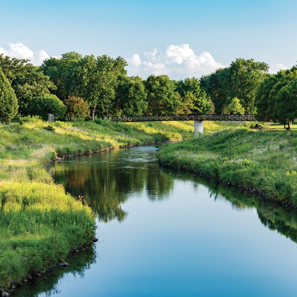 Bridge crosses stream in leafy park