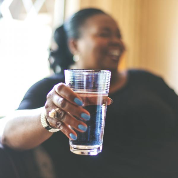 smiling woman holds glass of water