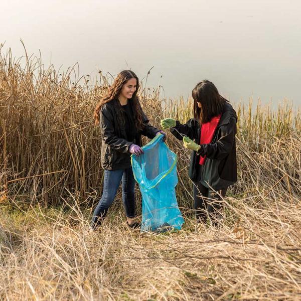Two young women in natural area pick up trash