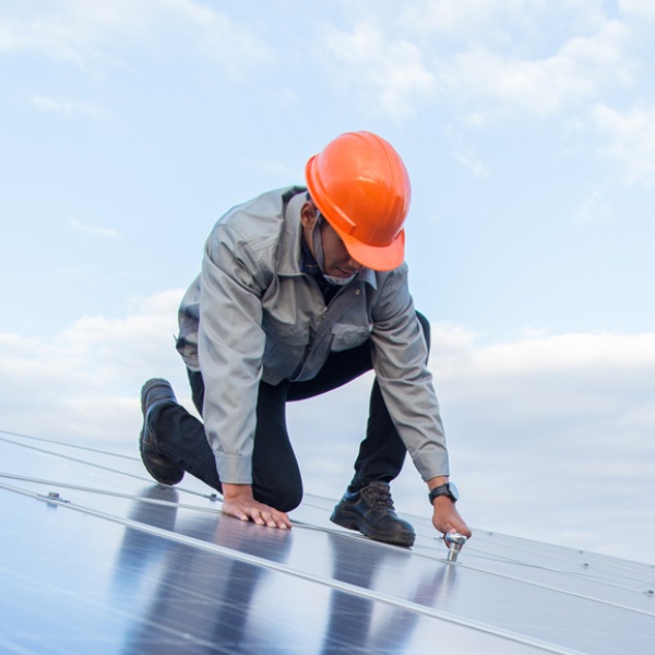 Worker in hard hat works on solar panel