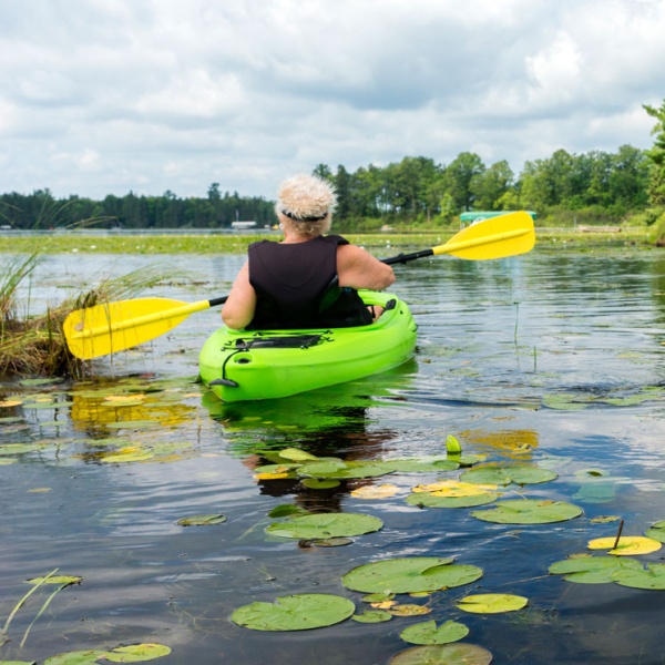 two people kayaking on a lake in summer