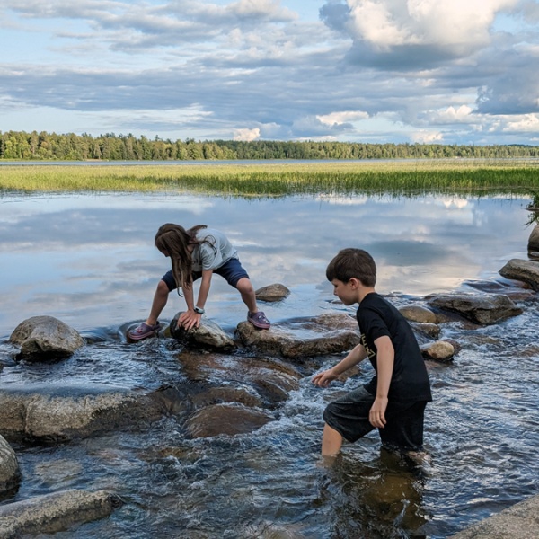 Kids climb over rocks in water